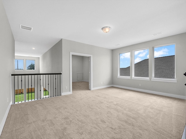 carpeted spare room featuring baseboards, a healthy amount of sunlight, and visible vents