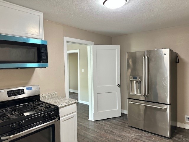 8230 Woodward St, Houston, TX 77051 - kitchen with baseboards, white cabinetry, appliances with stainless steel finishes, dark wood-style floors, and a textured ceiling