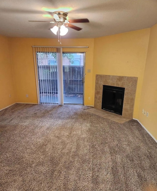 unfurnished living room with a tile fireplace, carpet flooring, baseboards, and ceiling fan