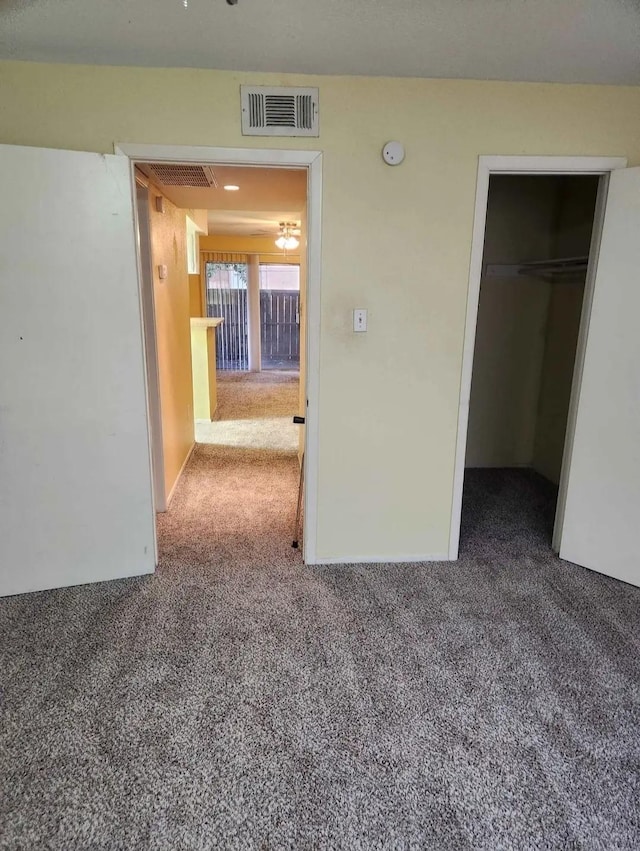 unfurnished bedroom with a spacious closet, carpet, visible vents, and a closet