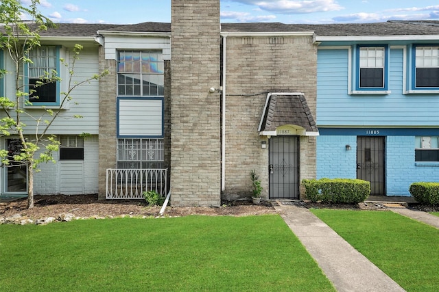 townhome / multi-family property featuring a chimney, a front lawn, and brick siding