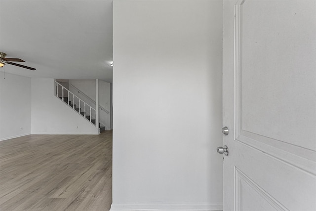 interior space featuring a ceiling fan, wood finished floors, and stairs