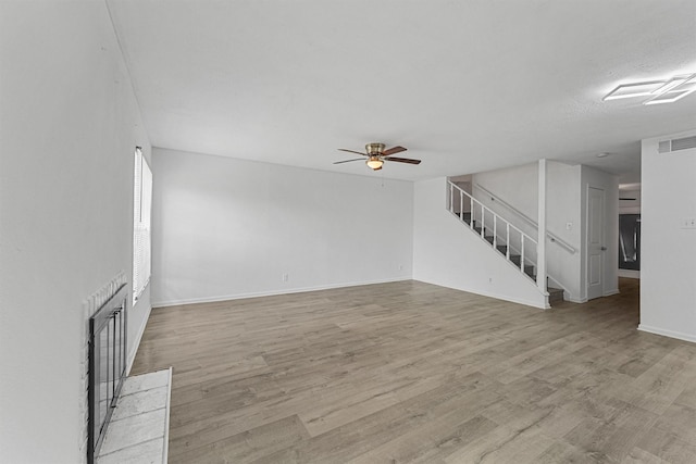 unfurnished living room featuring stairway, light wood-type flooring, ceiling fan, baseboards, and visible vents