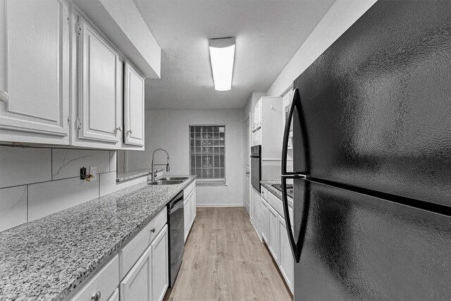 kitchen with black appliances, white cabinetry, a sink, and light wood finished floors