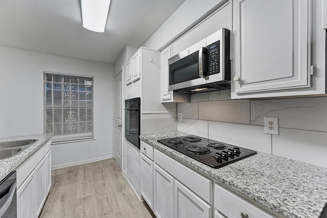 11887 Algonquin Dr, Houston, TX 77089 - kitchen with black appliances, light wood finished floors, decorative backsplash, white cabinets, and light stone counters