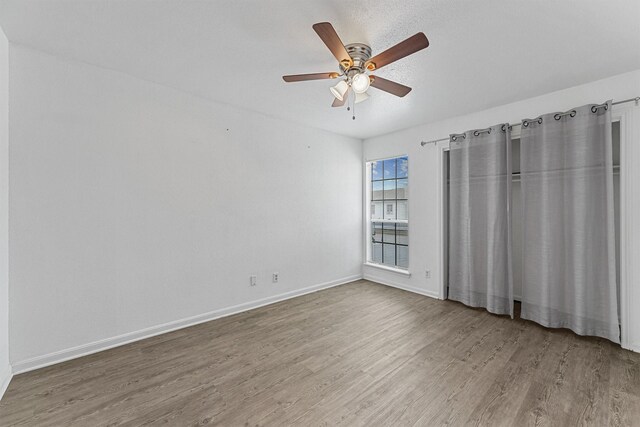unfurnished bedroom with wood finished floors, a ceiling fan, and baseboards