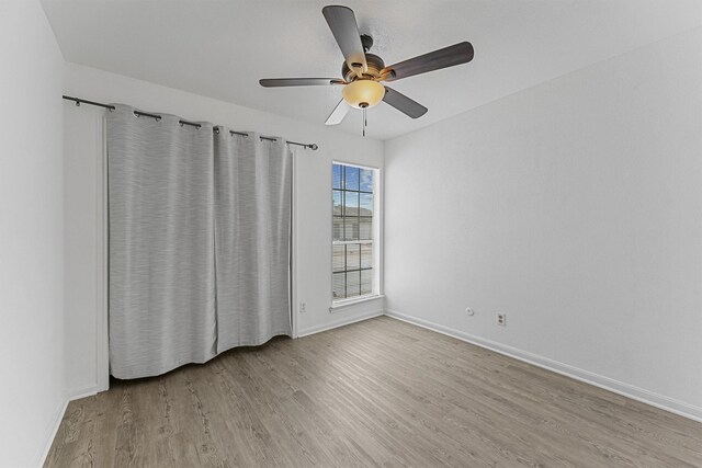 spare room featuring ceiling fan, baseboards, and wood finished floors