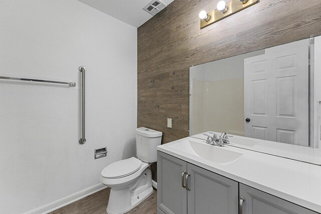 bathroom featuring wooden walls, wood finished floors, visible vents, vanity, and baseboards