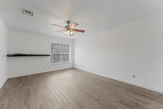 unfurnished room with wood finished floors, visible vents, baseboards, and ceiling fan