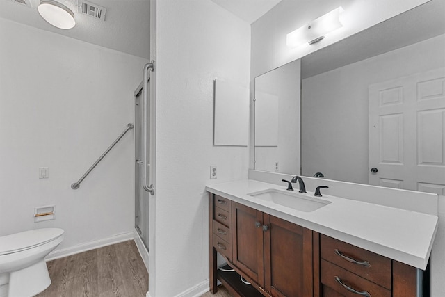 full bath with a stall shower, baseboards, visible vents, wood finished floors, and vanity