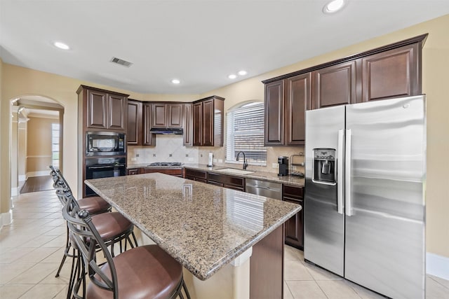 514 Whitney Oaks Ln, Stafford, TX 77477 - kitchen with dark brown cabinets, arched walkways, a healthy amount of sunlight, appliances with stainless steel finishes, and visible vents