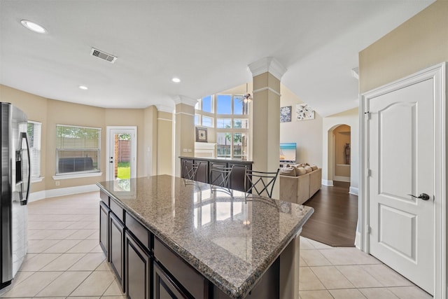514 Whitney Oaks Ln, Stafford, TX 77477 - kitchen featuring plenty of natural light, ornate columns, arched walkways, stainless steel fridge with ice dispenser, and a kitchen island