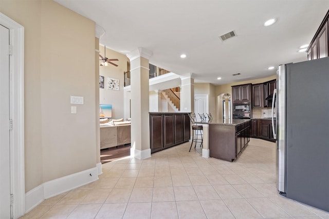 514 Whitney Oaks Ln, Stafford, TX 77477 - kitchen featuring dark brown cabinets, visible vents, freestanding refrigerator, black microwave, and a breakfast bar