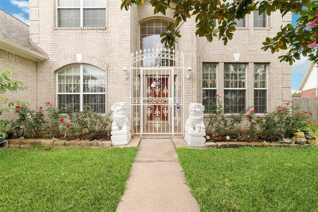 view of exterior entry with a lawn and brick siding