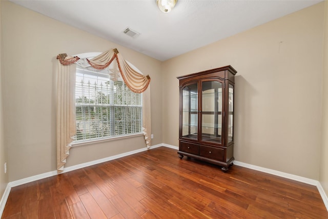 unfurnished room featuring hardwood / wood-style floors, baseboards, and visible vents