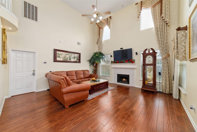living room with baseboards, a towering ceiling, visible vents, and a fireplace