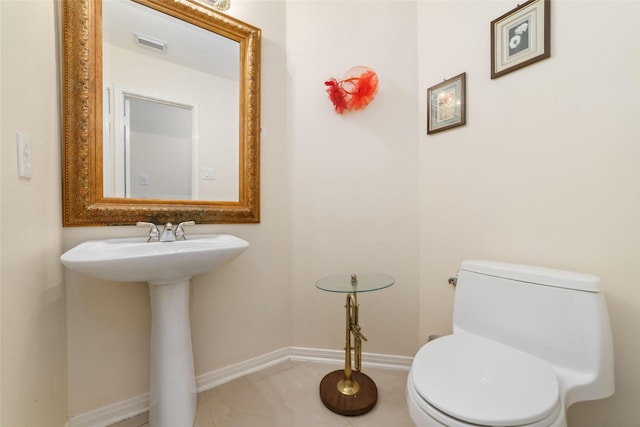 bathroom with tile patterned floors, visible vents, toilet, a sink, and baseboards