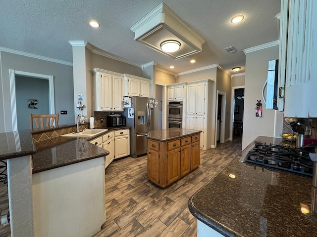 kitchen with a sink, stainless steel appliances, dark stone countertops, tasteful backsplash, and a peninsula