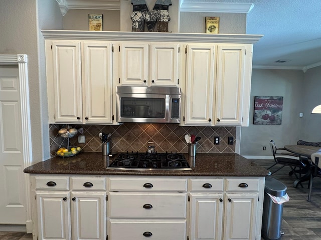 kitchen with black gas cooktop, stainless steel microwave, tasteful backsplash, and crown molding