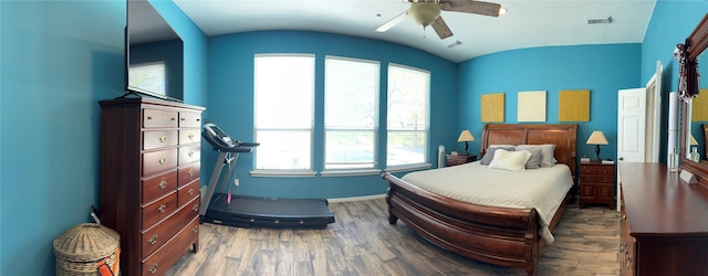 bedroom with wood finished floors, visible vents, a ceiling fan, and vaulted ceiling