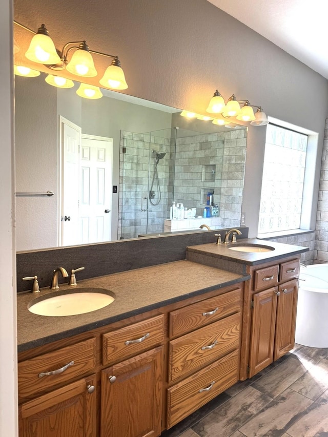 full bath with a walk in shower, a tub to relax in, wood finished floors, and a sink