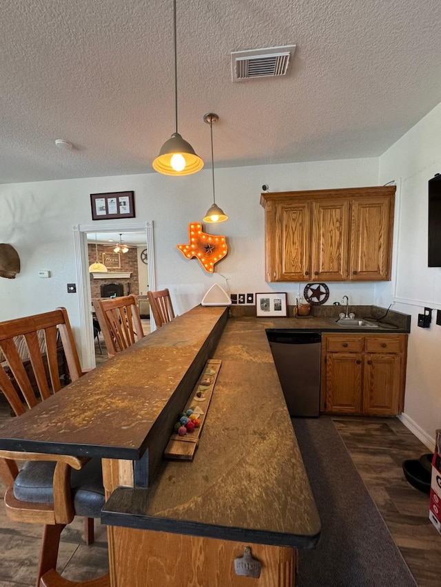 kitchen with dark countertops, brown cabinets, dishwasher, and visible vents