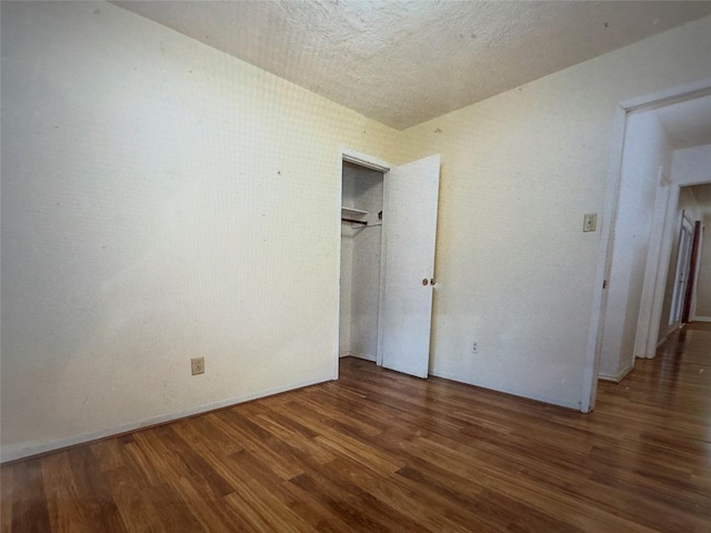 unfurnished bedroom featuring wood finished floors, a textured ceiling, and a closet