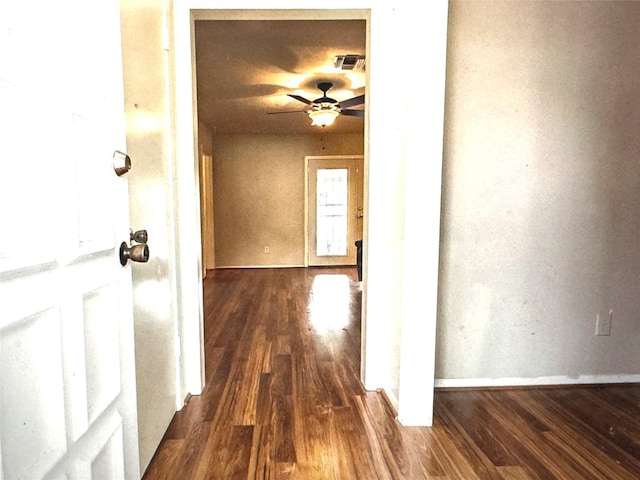 corridor featuring baseboards, visible vents, and dark wood finished floors