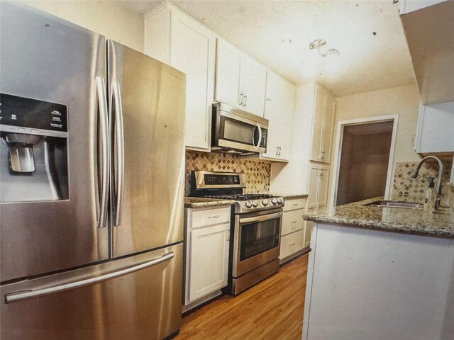 kitchen featuring a sink, light wood-style floors, appliances with stainless steel finishes, and tasteful backsplash