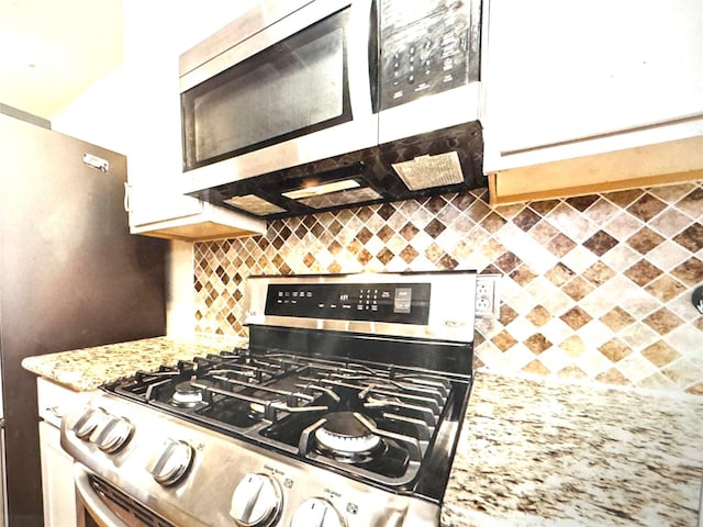 kitchen featuring stainless steel range with gas cooktop, tasteful backsplash, and light stone countertops