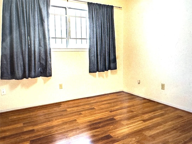 unfurnished room featuring baseboards and wood finished floors