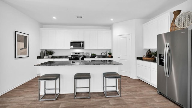 2707 Misty Elm Ln, Rosenberg, TX 77469 - kitchen featuring stainless steel appliances, recessed lighting, an island with sink, a breakfast bar area, and wood finished floors