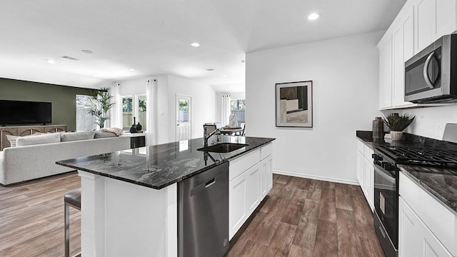 2707 Misty Elm Ln, Rosenberg, TX 77469 - kitchen with stainless steel appliances, a sink, an island with sink, dark wood-style floors, and dark stone countertops