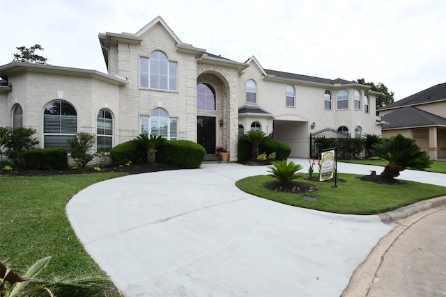 view of front of property featuring curved driveway, brick siding, and a front yard