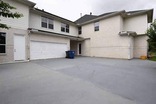 rear view of house with concrete driveway, brick siding, and a garage