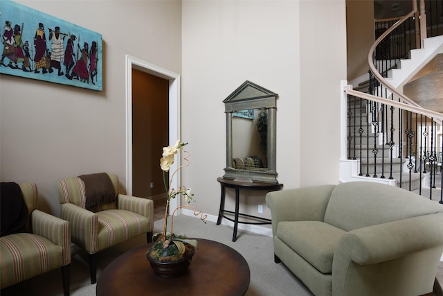 living area featuring carpet floors, baseboards, stairs, and a towering ceiling