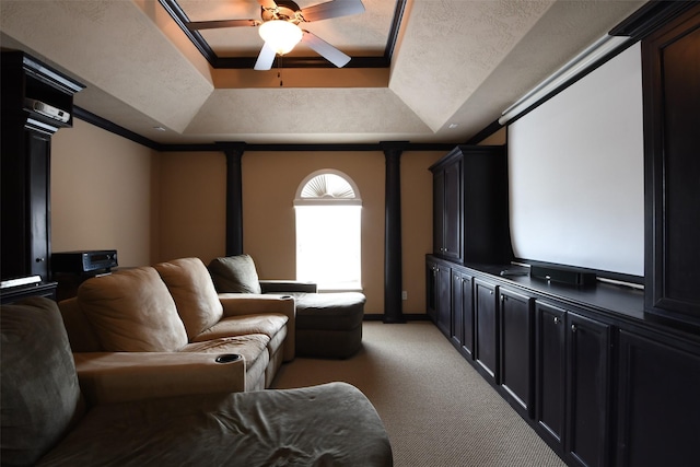 home theater room with a ceiling fan, light carpet, ornamental molding, and a raised ceiling