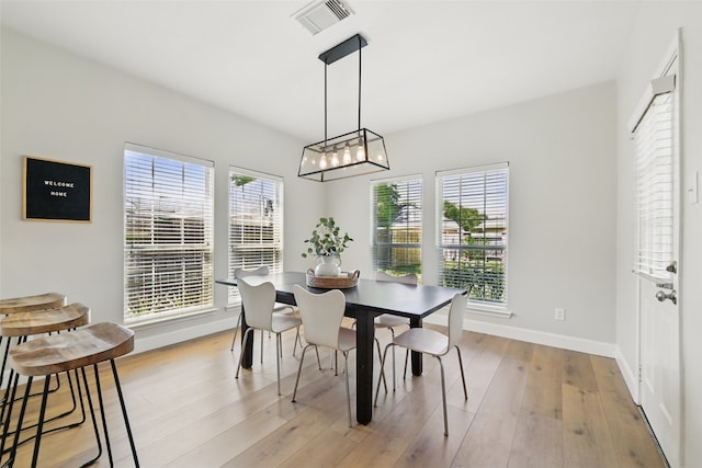 dining area with baseboards, a chandelier, visible vents, and light wood-style floors