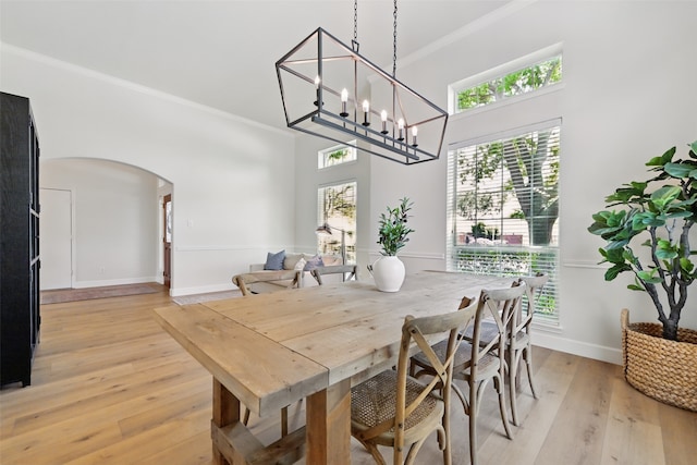 dining room featuring arched walkways, a high ceiling, a wealth of natural light, and crown molding