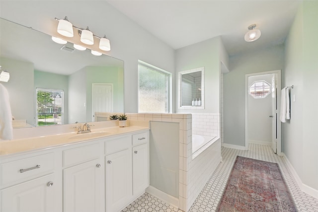 bathroom with a bath, tile patterned floors, baseboards, visible vents, and vanity