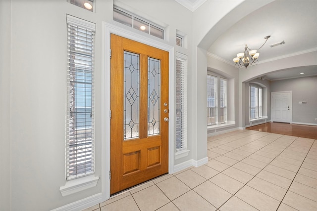 13611 Brookbluff Ln, Houston, TX 77077 - foyer featuring crown molding, light tile patterned floors, arched walkways, an inviting chandelier, and baseboards