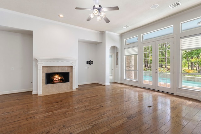 1614 Beau Rivage, Conroe, TX 77304 - unfurnished living room featuring hardwood / wood-style flooring, a fireplace, french doors, ornamental molding, and arched walkways