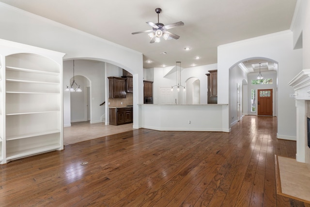 1614 Beau Rivage, Conroe, TX 77304 - unfurnished living room featuring ornamental molding, ceiling fan, arched walkways, a chandelier, and hardwood / wood-style floors