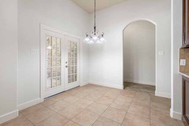 1614 Beau Rivage, Conroe, TX 77304 - unfurnished dining area with french doors, light tile patterned floors, arched walkways, a chandelier, and baseboards