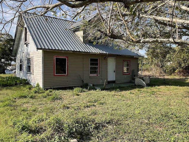 back of house with a lawn and metal roof