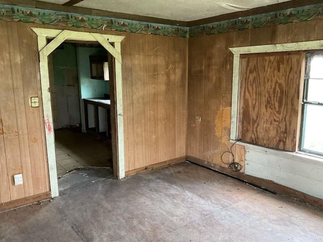 spare room featuring unfinished concrete floors and wood walls