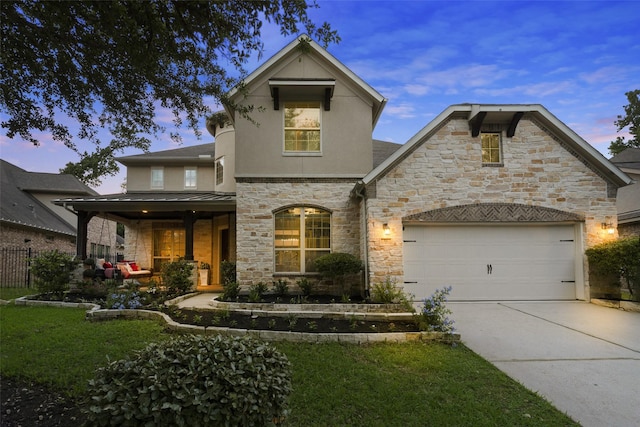 french provincial home with driveway, a garage, fence, stone siding, and stucco siding