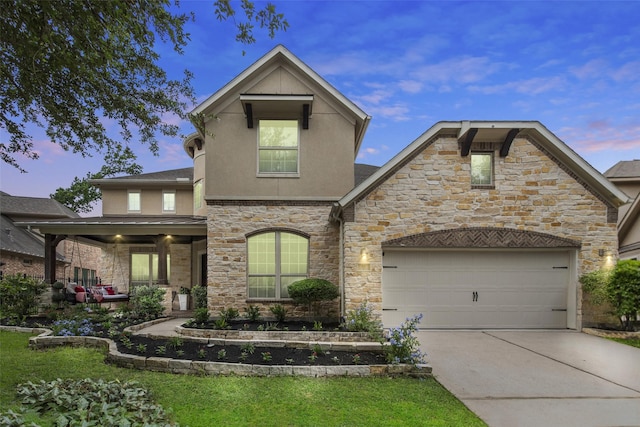 view of front of property featuring an attached garage, stucco siding, concrete driveway, and stone siding