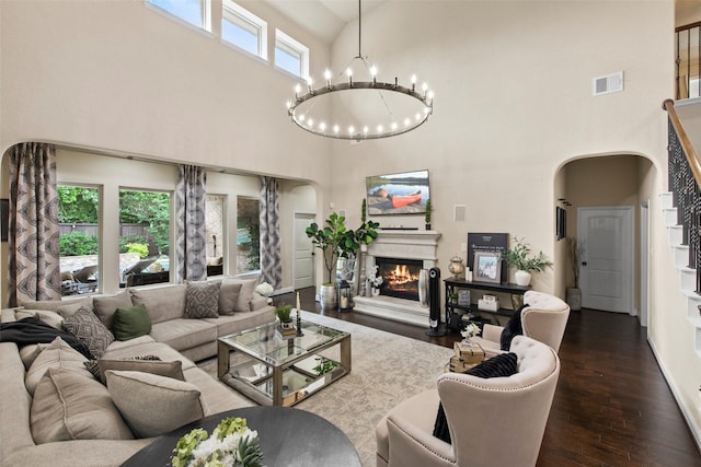 living area with visible vents, an inviting chandelier, a towering ceiling, dark wood-style floors, and arched walkways