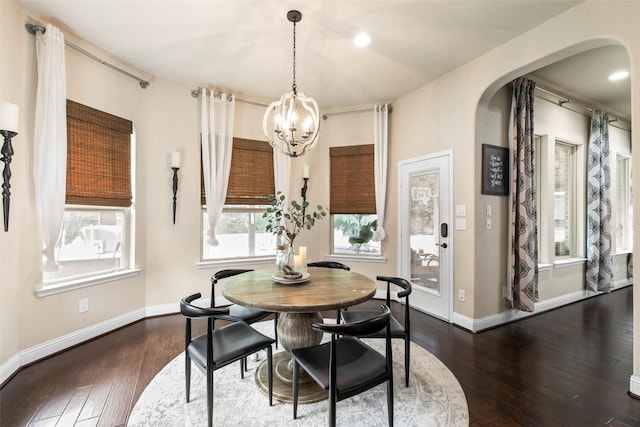 dining room featuring arched walkways, baseboards, dark wood-style flooring, and a notable chandelier